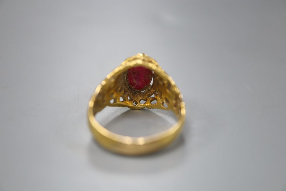 An Indian? pierced yellow metal and cabochon red stone set dress ring, size N/O, gross 8 grams.